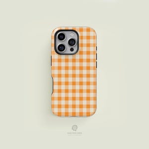 May include: A phone case with a classic orange and white gingham pattern. The case has a camera cutout and black side accents. The bottom of the case has the text "CASE FACE CASES".
