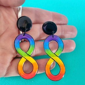 May include: Rainbow infinity symbol earrings with black tops. The earrings are made of resin and are painted with a rainbow gradient.