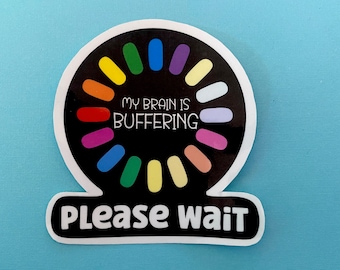 以下が含まれることがあります： 黒い背景にカラフルなローディングサークルデザインの丸いステッカー。「MY BRAIN IS BUFFERING」の文字が中央にあり、その下に「PLEASE WAIT」と書かれています。ステッカーは水色の表面にあります。