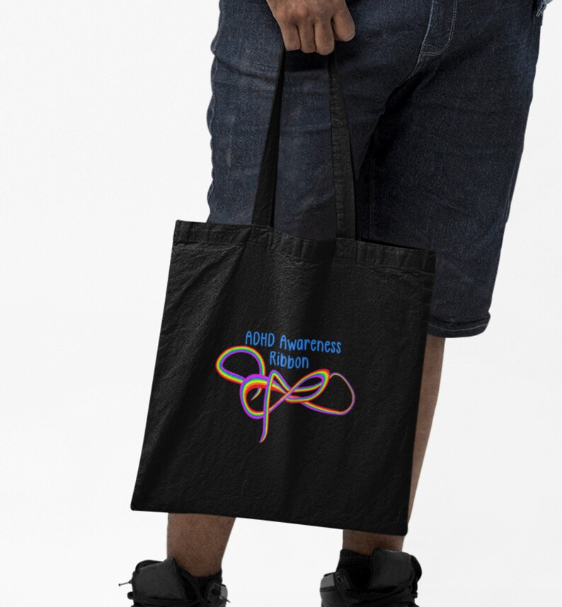 May include: Black tote bag with a rainbow ribbon design and the text "ADHD Awareness Ribbon".