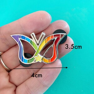 May include: Rainbow enamel pin shaped like a butterfly with a star in the center. The pin is 4 inches wide and 3.5 inches tall.