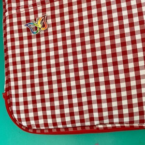 May include: A red and white gingham laptop sleeve with a rainbow butterfly pin.