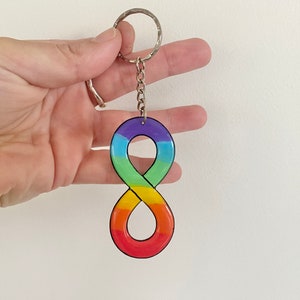 May include: Rainbow infinity symbol keychain with a silver key ring. The symbol is made of a hard plastic material and is painted with the colours of the rainbow.
