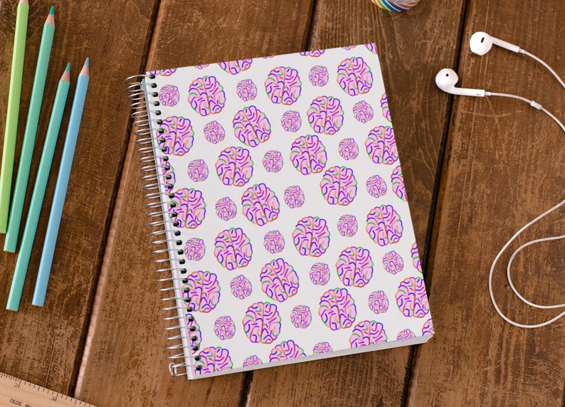 Puede incluir: Una libreta de espiral blanca con un patr&oacute;n de cerebro rosa, azul y verde.