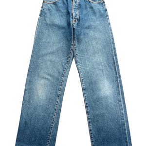 May include: Light blue denim jeans with a classic five-pocket design. The jeans have a button and zipper closure, belt loops, and a straight leg fit. The denim has a faded wash and subtle wear marks.