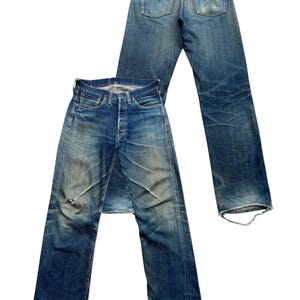 Może przedstawiać: Dwie pary dżins&oacute;w vintage z niebieskiego denimu. Jedna para leży płasko, pokazując prz&oacute;d z zapięciem na guziki i przetarciami. Druga para jest umieszczona z tyłu, pokazując tylne kieszenie i sk&oacute;rzaną naszywkę.