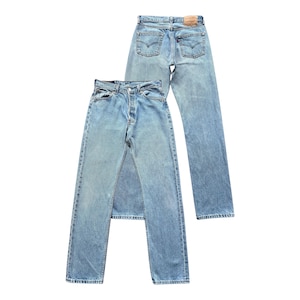 Puede incluir: Dos pares de vaqueros de mezclilla azul claro. Un par se muestra con la parte delantera hacia el espectador, y el otro par se muestra con la parte trasera hacia el espectador. Los vaqueros tienen un diseño clásico de cinco bolsillos y bragueta con botones.