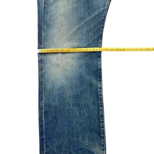 May include: Close-up of blue denim jeans with yellow measuring tape. The jeans are laid flat, showing the waist, thigh, and length measurements. The denim has a faded, worn appearance.