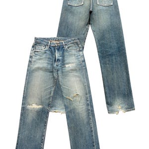 May include: Two pairs of light blue denim jeans with a faded wash and distressed details. One pair is laid flat, the other is upright, showing the back pockets and a leather patch. Both pairs have ripped knees and frayed hems.