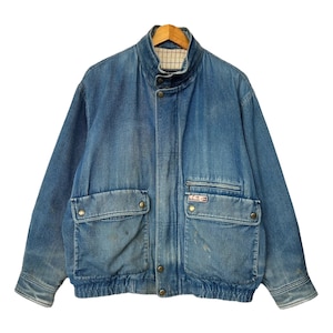 Könnte beinhalten: Vintage blaue Jeansjacke mit Stehkragen, zwei Frontklappentaschen und zwei Seitentaschen. Die Jacke hat eine Knopfleiste vorne und einen gerippten Saum. Der Denim hat einen verblichenen, abgenutzten Look.