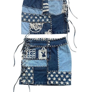 May include: Two denim skirts with a patchwork design. The skirts feature various shades of blue denim, with star and logo patches. Silver studs line the top and bottom edges. Each skirt has lace-up detailing on the sides.