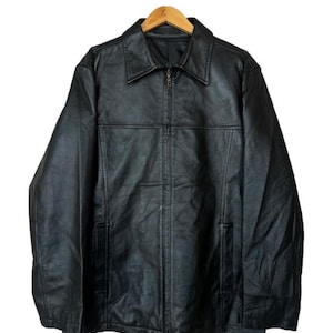 May include: A white ceramic mug with a black handle and the text "But First, Coffee" in a black, bold font. The mug is on a white surface.