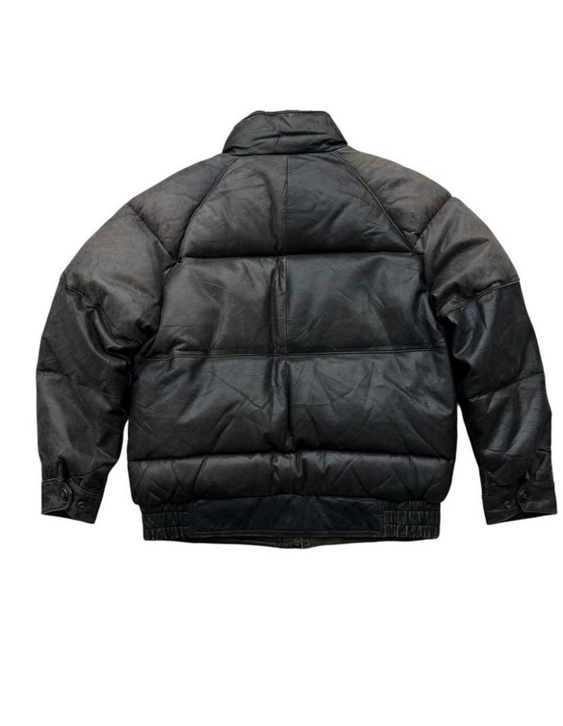 May include: A black leather puffer jacket with a high collar and ribbed cuffs. The jacket has a quilted design and a bomber-style fit. The leather appears worn, with a gradient from dark brown to black.