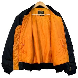 May include: Black bomber jacket with an orange interior. The jacket is hanging on a wooden hanger. The interior lining is a bright orange color, and the exterior is black. The jacket has a zipper closure and pockets.