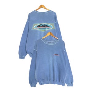 May include: Two blue sweatshirts with long sleeves are displayed. The front sweatshirt has a small logo on the chest, while the back of the other sweatshirt has a larger logo with the text "BOARDSHORT CO."