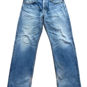 Pu&ograve; includere: Jeans di denim blu sbiadito con un classico design a cinque tasche. I jeans hanno una chiusura con bottoni e un aspetto invecchiato con sbiadimento e segni di usura. La vita presenta un piccolo accento rosso. I jeans sono un modello a gamba dritta.