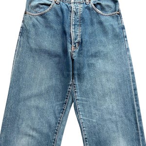 May include: Light blue denim jeans with a classic five-pocket design. The jeans feature a button and zipper closure, belt loops, and a faded wash for a vintage look. The stitching is visible in a contrasting color.