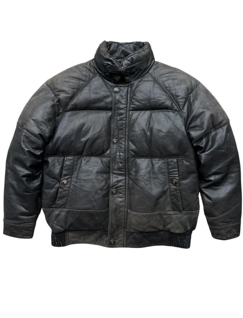 May include: A black leather puffer jacket with a high collar and button-up front. The jacket has two front pockets and a ribbed hem. The leather appears worn, giving it a vintage look. A classic outerwear piece.
