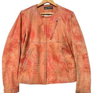 May include: A light orange leather jacket with a zipper closure and a label that reads "ISSEY MIYAKE".