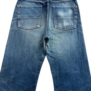 Puede incluir: Vaqueros de mezclilla azul descolorido con dos bolsillos traseros y un parche de cuero. Los vaqueros tienen un dise&ntilde;o cl&aacute;sico de cinco bolsillos y un corte recto. El nombre de la marca "EDWIN" es visible en el parche de cuero.