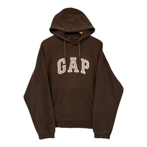 May include: A brown hooded sweatshirt with the GAP logo in beige letters across the chest. The sweatshirt has a front pocket and a drawstring at the hood. The garment is made of a soft material.