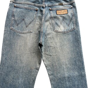 K&ouml;nnte beinhalten: Hellblaue Jeans mit dem Wrangler-Logo auf der Ges&auml;&szlig;tasche. Die Jeans haben ein klassisches F&uuml;nf-Taschen-Design mit verwaschener Optik und geradem Bein. Die Ges&auml;&szlig;taschen haben die charakteristische Wrangler-Naht.