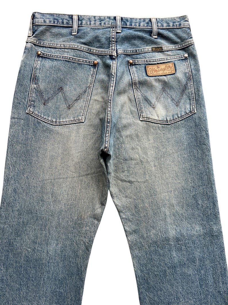 K&ouml;nnte beinhalten: Hellblaue Jeans mit dem Wrangler-Logo auf der Ges&auml;&szlig;tasche. Die Jeans haben ein klassisches F&uuml;nf-Taschen-Design mit verwaschener Optik und geradem Bein. Die Ges&auml;&szlig;taschen haben die charakteristische Wrangler-Naht.