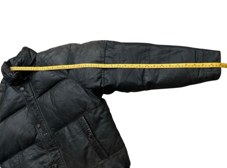 May include: Black puffer jacket with a yellow measuring tape across the sleeve. The jacket has a button closure and two pockets. The sleeve measures approximately 30 inches.
