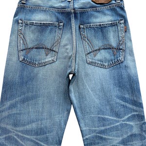 Pu&ograve; includere: Jeans di denim blu chiaro con dettagli usurati e cuciture a vista. Le tasche posteriori presentano un design unico e un'etichetta in pelle marrone con il marchio "EDWIN" &egrave; visibile. Fatto in Giappone.