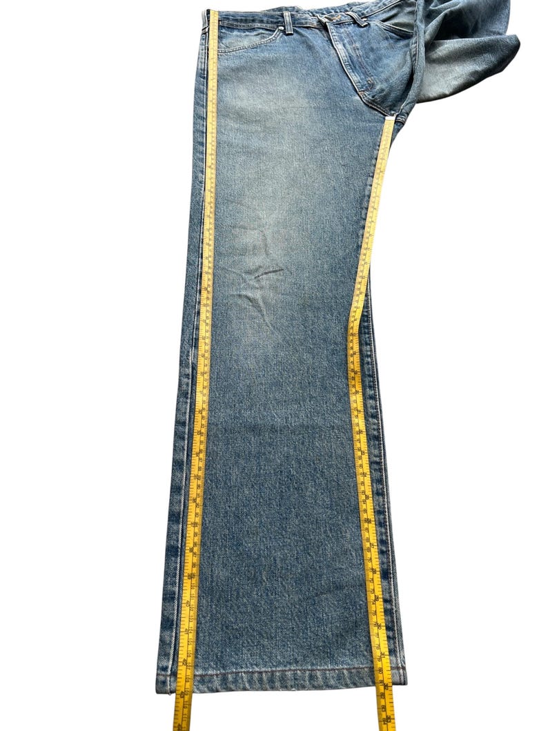 K&ouml;nnte beinhalten: Hellblaue Jeans mit geradem Bein. Ein gelbes Ma&szlig;band wird entlang der Jeans platziert. Die Jeans ist etwa 102 cm lang.