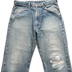 K&ouml;nnte beinhalten: Hellblaue Jeans aus Denim mit verwaschener Optik und Used-Details. Die Jeans haben einen klassischen F&uuml;nf-Taschen-Stil, einen Knopf- und Rei&szlig;verschluss und eine entspannte Passform. Der Denim hat ein abgenutztes Aussehen mit einem Riss am rechten Bein.