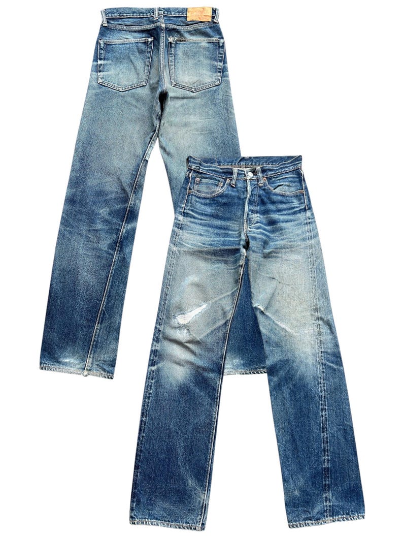 Pu&ograve; includere: Due paia di jeans vintage in denim blu. Un paio &egrave; visto da dietro, mostrando le tasche e la cintura. L'altro paio &egrave; davanti, mostrando le tasche anteriori, la chiusura con bottoni e i dettagli usurati. I jeans hanno un aspetto sbiadito e usurato.