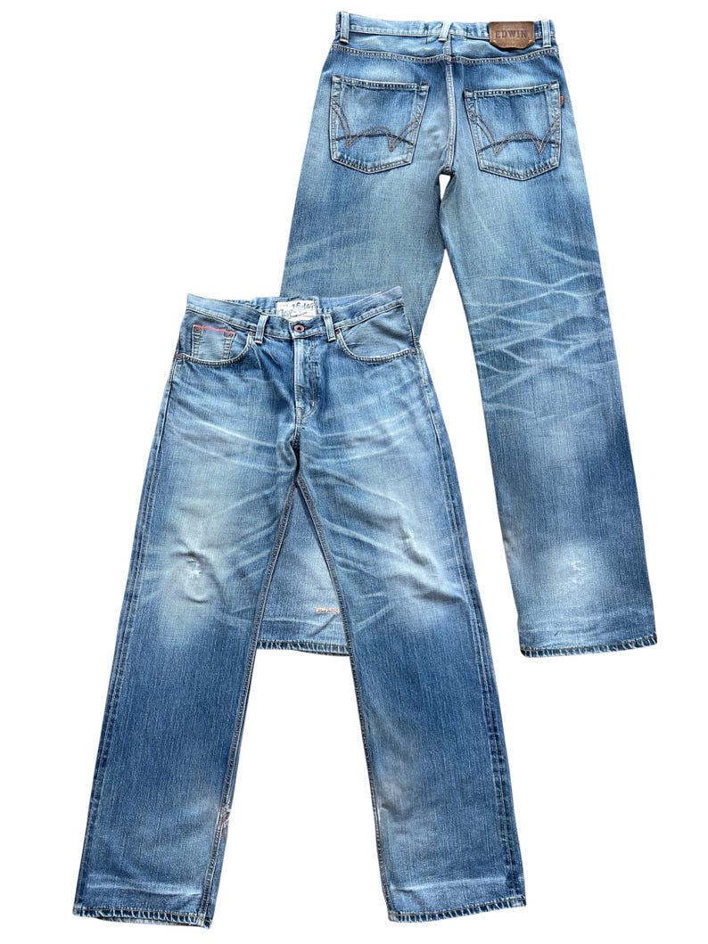 Pu&ograve; includere: Due paia di jeans in denim blu chiaro. Un paio &egrave; steso, mostrando la parte anteriore con la chiusura a bottoni e le tasche. L'altro paio &egrave; in piedi, mostrando le tasche posteriori e una toppa in pelle. Entrambi i jeans hanno un aspetto usurato e sbiadito.