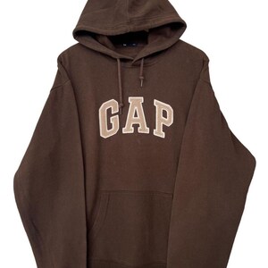 May include: A brown hooded sweatshirt with a large tan embroidered "GAP" logo on the front.