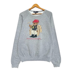 May include: A gray Polo Bear sweatshirt with a graphic of a bear wearing a red cap, tan jacket, and a football jersey with the number 2. The text "POLO BEAR by RALPH LAUREN" is printed below the bear.