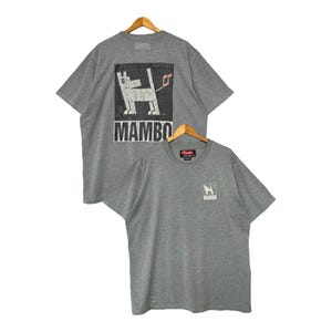 May include: Two grey t-shirts with a graphic print of a dog on the back and front. The back of the shirt says "Mambo".