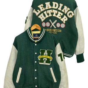 以下が含まれることがあります： 緑と白のバーシティージャケットで、背面に「LEADING HITTER」と刺繍されています。ジャケットは、前面に「HARVARD SPORTS CLUB MEMBERS」と刺繍された白いHがあります。