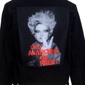 以下が含まれることがあります： 背面にモホークの髪型をした人物の白黒写真と「Only Anarchists Are Pretty」という赤い文字が書かれたパッチが付いた黒いデニムジャケットです。