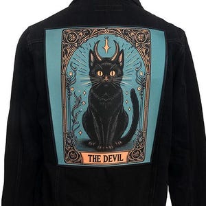 May include: Black denim jacket with a large, colourful patch on the back. The patch features a black cat with a crescent moon above its head and the words "THE DEVIL" below.