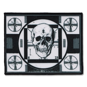 May include: Black and white embroidered patch featuring a skull in the centre of a classic television test pattern. The skull has a cross on its forehead and a slight smile.