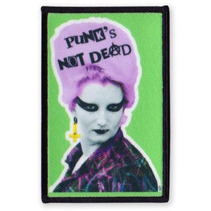 Könnte beinhalten: Ein gestickter Aufnäher mit dem Gesicht einer Frau und dem Text "Punk's Not Dead" auf grünem Hintergrund.