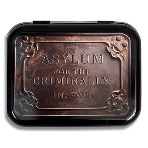 May include: A black metal box with a copper-coloured plaque that reads "Asylum for the Criminally Insane".