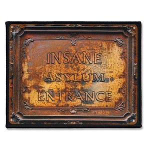 Può includere: Un cartello di metallo arrugginito con una cornice decorata recita "INSANE ASYLUM. ENTRANCE".