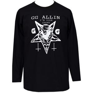 Puede incluir: Camiseta negra de manga larga con un gráfico blanco que presenta una estrella, una calavera y cruces invertidas. El texto "GG ALLIN I'M YOUR ENEMY" está impreso encima del gráfico, con la letra "G" a cada lado de la estrella.