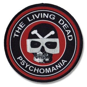 Könnte beinhalten: Ein schwarzer und roter runder Patch mit dem Text "The Living Dead Psychomania" um einen weißen Schädel mit gekreuzten Knochen, der eine weiße Schutzbrille trägt.