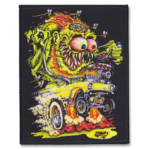 May include: Black rectangular patch with a cartoon monster driving a yellow hot rod. The monster has large red eyes and a toothy grin. The car is emitting flames and smoke. The patch includes the text "SHORTY".