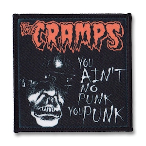 Può includere: Toppa in bianco e nero con il testo "The Cramps" in rosso e il testo "You Ain't No Punk You Punk" in bianco. La toppa presenta un'illustrazione in bianco e nero di un viso.