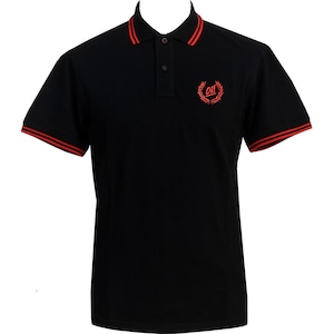 以下が含まれることがあります： 襟と袖に赤いトリムが付いた黒いポロシャツ。シャツの左胸には、花輪の中に「OH」と書かれた小さな刺繍ロゴがあります。