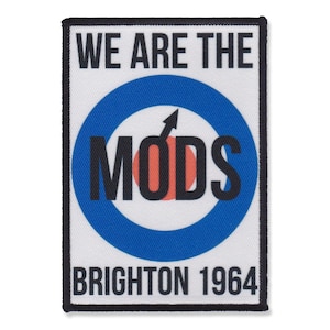 Peut inclure: Un patch blanc avec du texte noir qui dit "We are the Mods Brighton 1964". Un symbole de cible bleu et blanc avec un centre rouge et une flèche noire est au centre du patch.