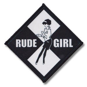 Könnte beinhalten: Ein schwarzer und weißer rautenförmiger Patch mit den Worten "RUDE GIRL" in weißer Schrift. Eine Schwarzweißillustration einer Frau in Rock und Oberteil befindet sich in der Mitte des Patches.